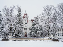 Main entrance of College Hall and surrounding trees blanketed in snow.